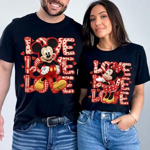 May include: Black t-shirts featuring Mickey and Minnie Mouse with the word "LOVE" in a red and white heart design. Mickey is wearing red shorts and yellow shoes. Minnie is wearing a red polka dot dress.