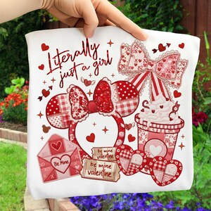May include: White tote bag featuring Valentine's Day themed graphics. The design includes a Minnie Mouse ear headband, a bow, hearts, an envelope, and a coffee cup. Text on the bag reads "Literally just a girl" and "Be Mine".
