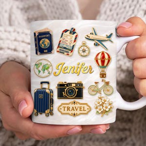 Könnte beinhalten: Weiße Keramiktasse mit Reise-Motiven, darunter ein Reisepass, eine Bordkarte, ein Flugzeug und ein Heißluftballon. Der Name "Jenifer" ist in goldener Schrift geschrieben. Die Tasse wird von einer Person gehalten.