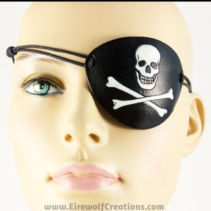 Handmade leather eyepatch with a skull-and-bones Jolly Roger carved into the leather and painted bone-white on a black background.