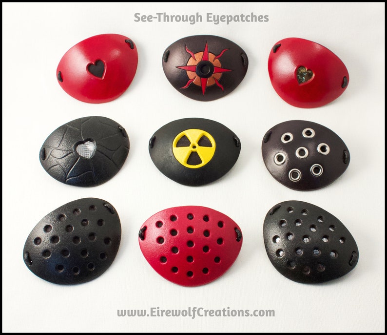 An assortment of see-through handmade leather eye patches in various designs, including hearts, compass rose, radiation hazard, grommets, and perforated. All but the grommets are backed with translucent fabric, either black, silver, or gold colored.