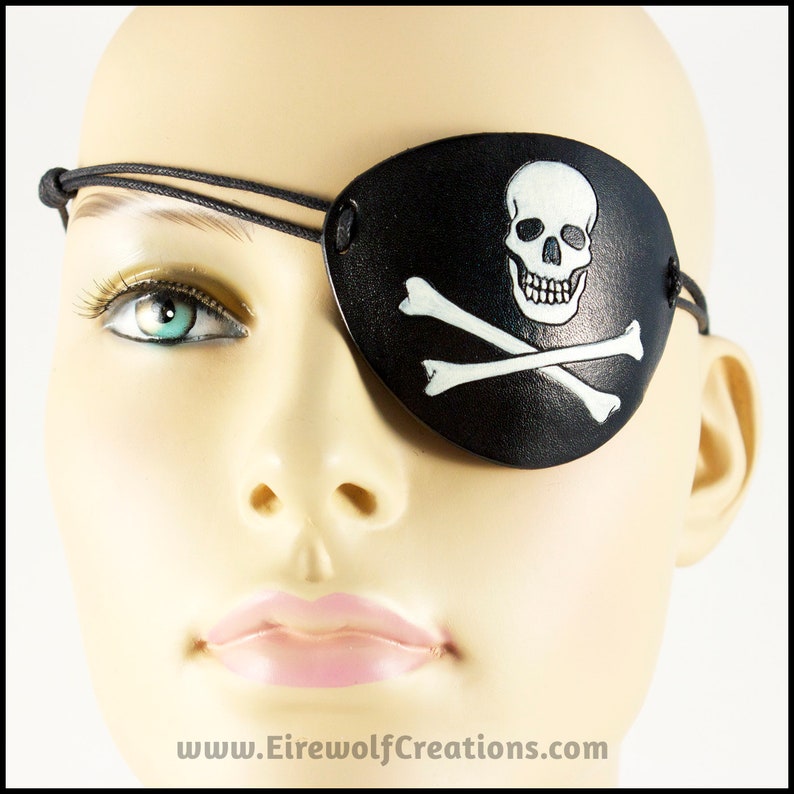 Handmade leather eyepatch with a skull-and-bones Jolly Roger carved into the leather and painted bone-white on a black background.