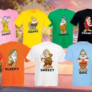 Könnte beinhalten: Sieben T-Shirts in verschiedenen Farben mit den sieben Zwergen aus dem Disney-Film Schneewittchen und die sieben Zwerge. Jedes Shirt zeigt einen anderen Zwerg mit seinem Namen darunter. Die Zwerge sind Dopey, Happy, Bashful, Grumpy, Sleepy, Sneezy und Doc.