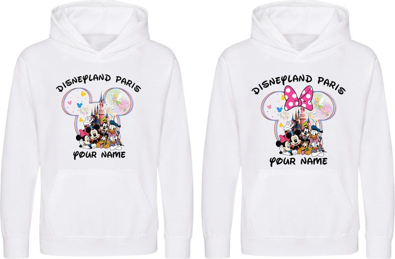 May include: Two white hooded sweatshirts with a Disneyland Paris graphic. The graphic features Mickey and Minnie Mouse, Donald Duck, and Goofy in front of a castle. The text "Disneyland Paris" and "Your Name" are also displayed.
