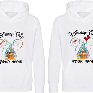 May include: Two white hooded sweatshirts with a Disney Trip design. The design includes the text "Disney Trip 2025" and a castle graphic with Disney characters. The bottom of the design has space for a name.