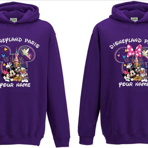 May include: Two purple hoodies with a Disneyland Paris design. The design features Mickey Mouse, Minnie Mouse, Donald Duck, and other characters. The text "Disneyland Paris" and "Your Name" are also printed on the front.