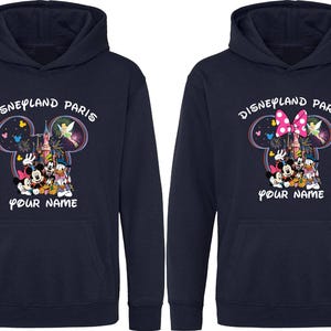 May include: Navy blue hooded sweatshirts with a Disneyland Paris graphic. The design features Mickey and Minnie Mouse, Donald Duck, and other characters. The text "YOUR NAME" is below the graphic.
