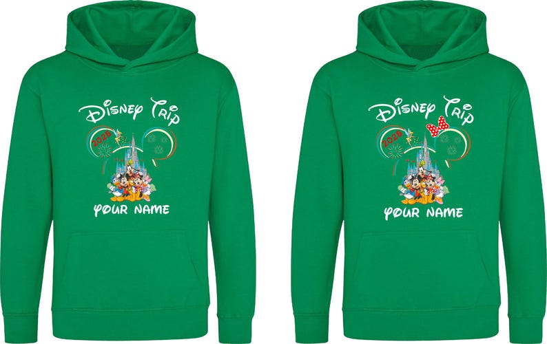 May include: Two green hooded sweatshirts with the text "Disney Trip" and "YOUR NAME" printed in white. The design includes a castle, Mickey Mouse ears, and Disney characters. One sweatshirt has a red bow.