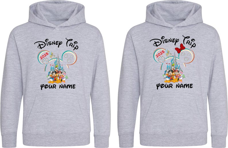 May include: Two light gray hoodies with a Disney Trip 2025 design. The design includes Mickey Mouse ears, a castle, and Disney characters. The text "YOUR NAME" is below the graphic. One hoodie has a red bow.