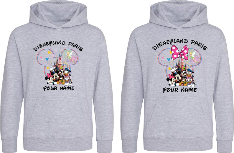 May include: Two light gray hoodies with a Disneyland Paris graphic. The graphic includes Mickey Mouse, Minnie Mouse, Donald Duck, and other Disney characters. The text "Disneyland Paris" and "Your Name" are also printed on the hoodies.