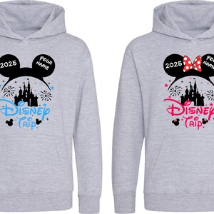 K&ouml;nnte beinhalten: Zwei hellgraue Kapuzenpullover mit Disney-Motiven. Einer hat blauen Text und eine schwarze Silhouette von Mickey Mouse-Ohren mit "2025" und "Your Name". Der andere hat rosa Text und eine Minnie Mouse-Schleife.