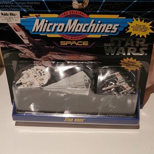 May include: A Micro Machines Star Wars Space scale miniatures set in original packaging. The blister pack contains a Millennium Falcon, a Star Destroyer, and an X-wing Starfighter. The blue and black cardboard backing features the Star Wars logo.