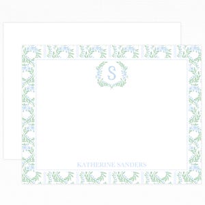 May include: White stationery set featuring a floral border in light blue and green. The design includes a monogrammed wreath with the letter "S" and the name "Katherine Sanders" printed in a delicate font. Includes a matching envelope.