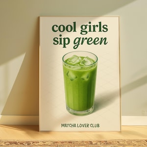 May include: A framed print featuring the words "cool girls sip green" above a glass of green matcha with ice cubes. The text "Matcha Lover Club" is at the bottom. The background is a light beige colour.