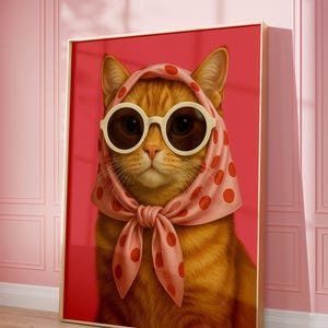 May include: A framed print of a ginger cat, sporting white sunglasses and a pink scarf with red spots. The cat is set against a red backdrop. A fun and fashionable image, suitable for home decor.