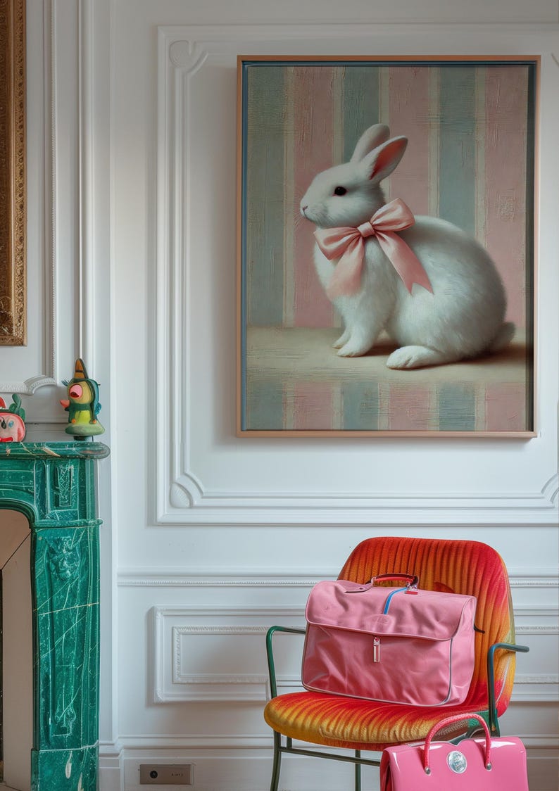 Op de afbeelding: Een wit konijn met een roze strik zit op een roze en blauwe gestreepte achtergrond in een ingelijst schilderij. Het schilderij hangt aan een witte muur in een kamer met een groene marmeren open haard en een roze en oranje gestreepte stoel.