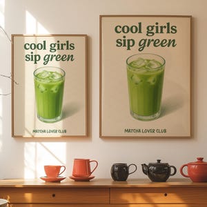 May include: Two framed posters with the text "cool girls sip green" and a green drink with ice. Below the text is "MATCHA LOVER CLUB". Below the posters are orange teacups and teapots.
