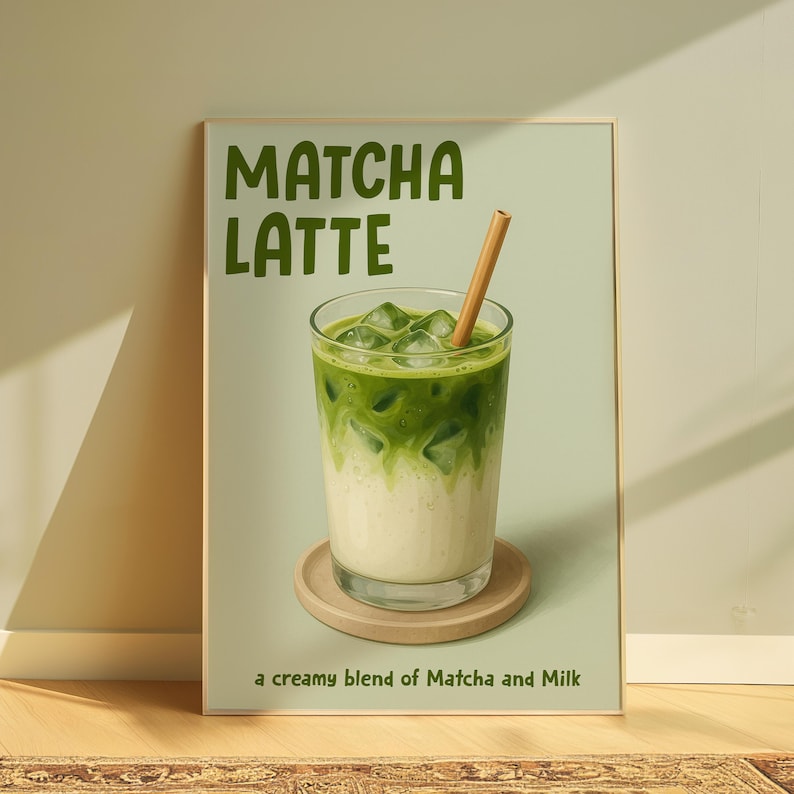 May include: A framed print depicting a matcha latte. The image shows a glass of layered green matcha and white milk with ice cubes, a wooden straw, and a wooden coaster. The text "Matcha Latte" is at the top, with "a creamy blend of Matcha and Milk" at the bottom.