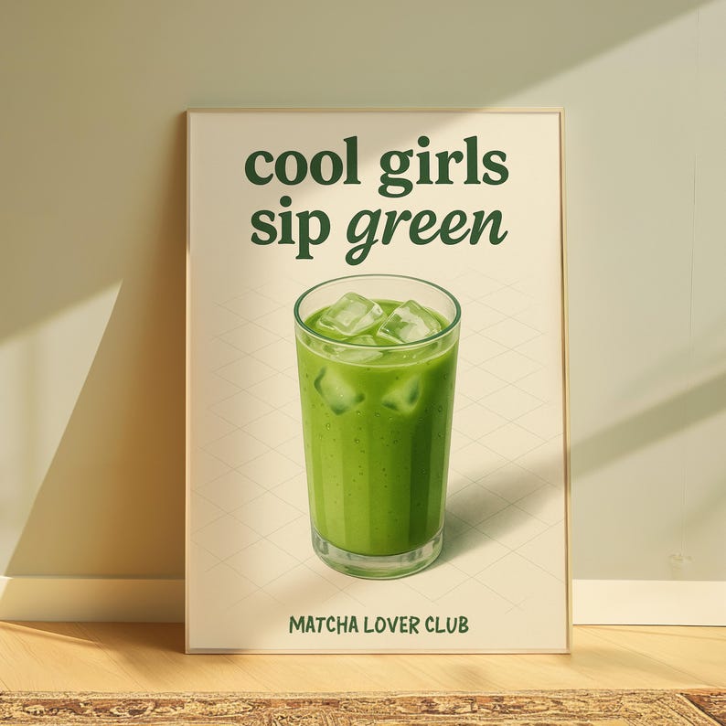 May include: A framed print featuring the words "cool girls sip green" above a glass of green matcha with ice cubes. The text "Matcha Lover Club" is at the bottom. The background is a light beige colour.