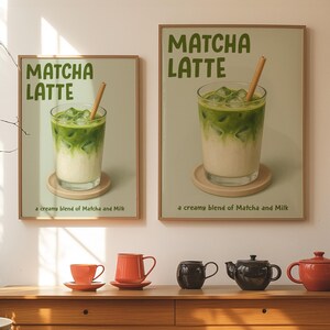 May include: Two framed prints of Matcha Latte drinks with a wooden straw. The prints are above a wooden table with orange and black teacups and teapots. The prints have the text "MATCHA LATTE" and "a creamy blend of Matcha and Milk".