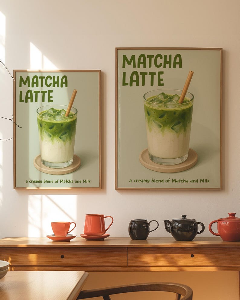 May include: Two framed prints of Matcha Latte drinks with a wooden straw. The prints are above a wooden table with orange and black teacups and teapots. The prints have the text "MATCHA LATTE" and "a creamy blend of Matcha and Milk".
