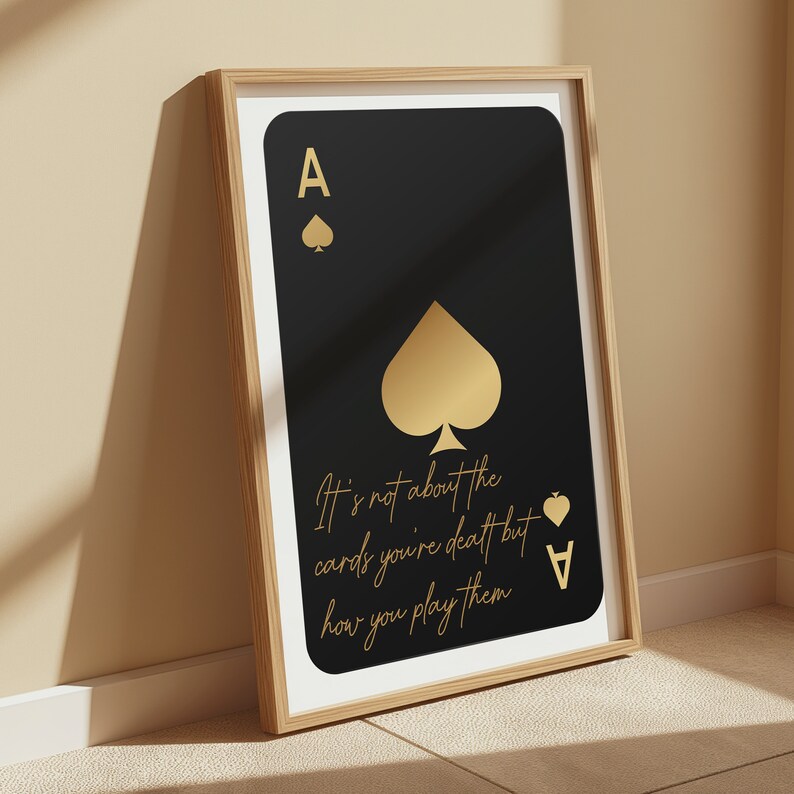 Pode incluir: Uma impress&atilde;o emoldurada preta e dourada com um design de carta de jogo de &aacute;s de paus dourado. O texto na impress&atilde;o diz "N&atilde;o se trata das cartas que voc&ecirc; recebe, mas de como voc&ecirc; as joga."
