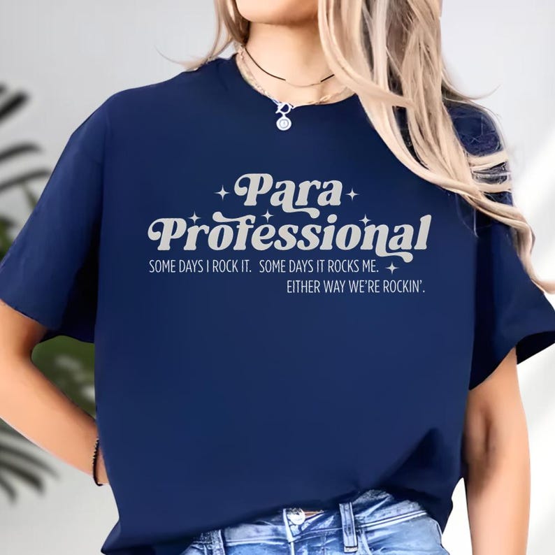 A person wearing a navy blue t-shirt with white text that says "Para Professional" and "Some days I rock it. Some days it rocks me. Either way we're rockin'."