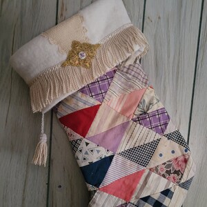 May include: A handmade Christmas stocking with a patchwork design. The body is made of various fabric scraps in triangles of different patterns and colors. The cuff is white with fringe and a gold embellishment.