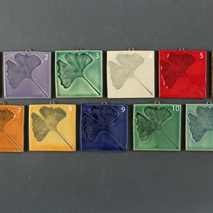May include: Eleven ceramic tiles with a ginkgo leaf design in various colors, including purple, green, white, red, brown, orange, yellow, blue, and green. The tiles are arranged in two rows, with numbers 1 through 11 printed on each tile.