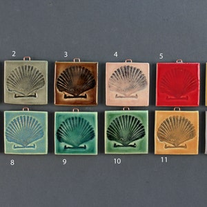 May include: Twelve ceramic tiles with a seashell design in various colors, including blue, green, yellow, red, and brown. Each tile has a small hole at the top for hanging.