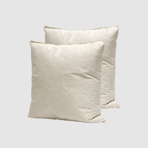 May include: Two white pillowcases, made of a soft, natural fabric, are stacked on top of each other.