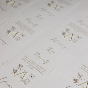 May include: A set of white cards with gold lettering and illustrations. The cards have the words "Prezenty" and "Informacje" on them. The illustrations are of a gift box, a house, and a letter.