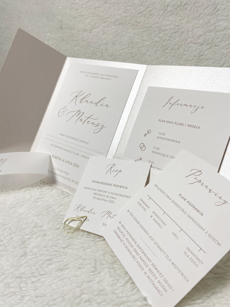 May include: A wedding invitation suite with a white background and gold accents. The invitation features the names "Klaudia & Mateusz" in a script font. The RSVP card includes the text "Potwierdzenie Przybycia" and the date "30 Kwietnia 2024". The information card includes a schedule for the wedding day, with times for the ceremony, reception, and after-party. The invitation also includes a map of the venue.