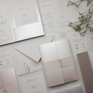 May include: A set of wedding invitations with a modern, minimalist design. The invitations are printed on white cardstock with gold foil accents. The text on the invitations includes the names "Martyna & Michal" and the date "SOBOTA, 28 WRZESNIA 2014".