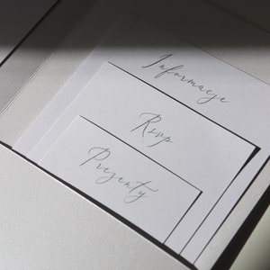 May include: A white envelope with three white cards inside. The cards are labeled "Information", "RSVP", and "Presents".
