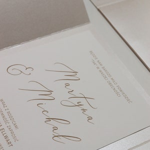 May include: A white wedding invitation with the names "Martyna" and "Michal" written in cursive script. The text "Będzie nam bardzo miło powiedziedzieć "TAK" w waszej obecności" is also included.