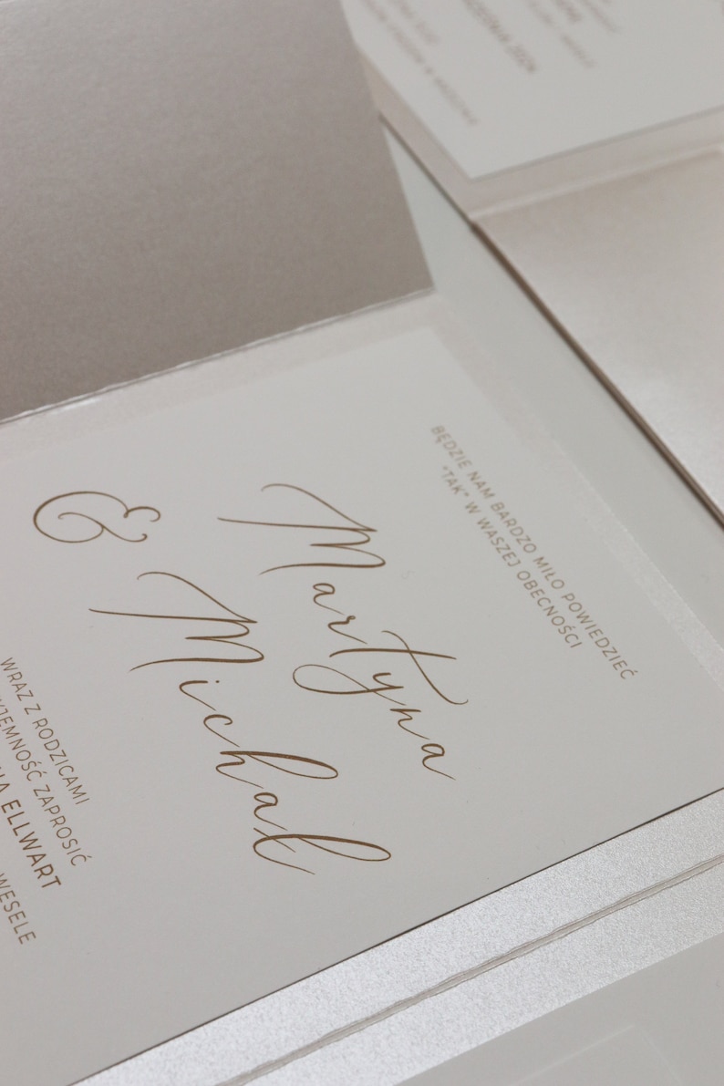 May include: A white wedding invitation with the names "Martyna" and "Michal" written in cursive script. The text "Będzie nam bardzo miło powiedziedzieć "TAK" w waszej obecności" is also included.