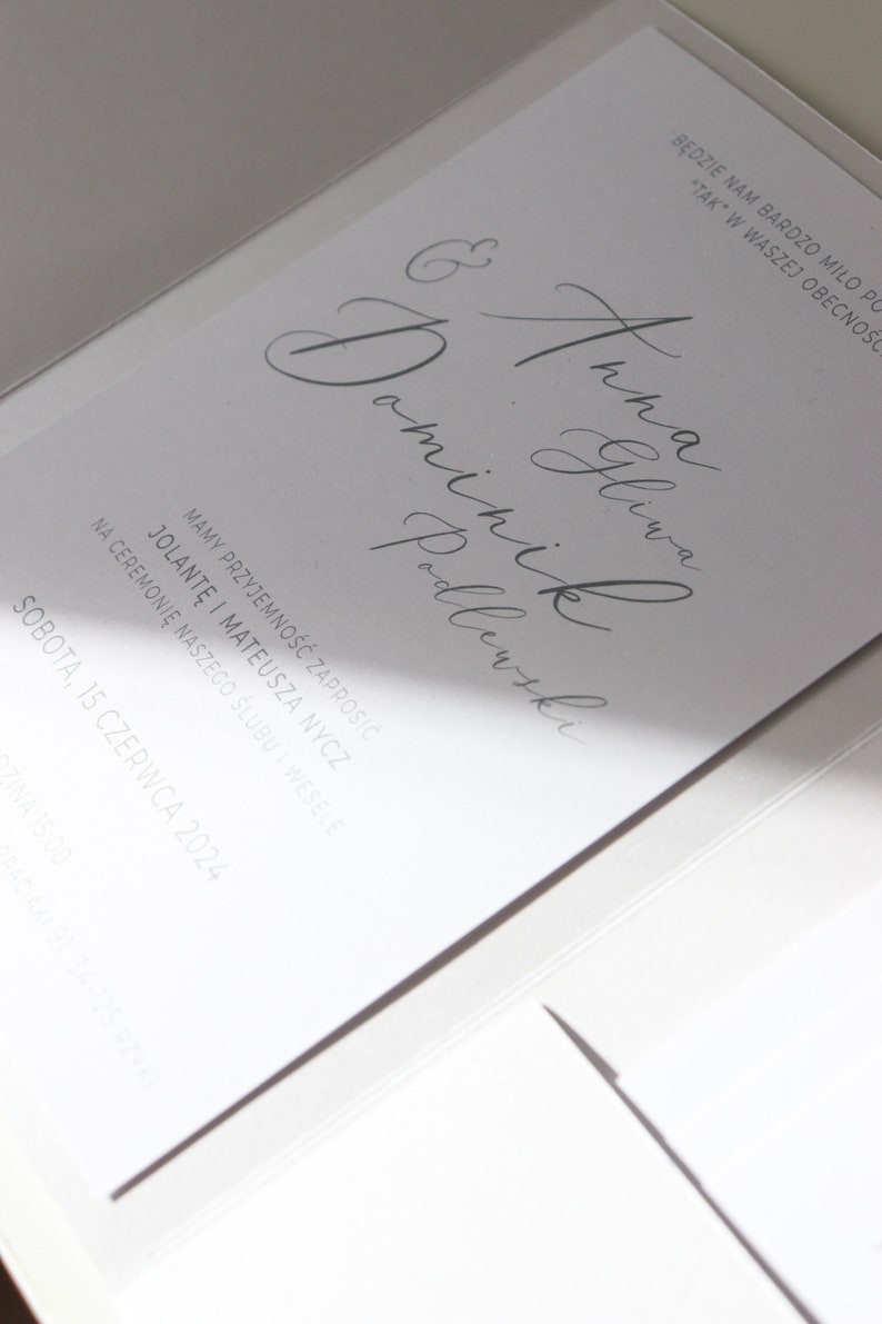 May include: A white wedding invitation with the text "BĘDZIE NAM BARDZO MIŁO PO "TAK" W WASZEJ OBECNOŚCI" and "& Anna Gliwa Dominik Podlewski" in cursive script. The invitation also includes the date "SOBOTA, 15 CZERWCA 2024".