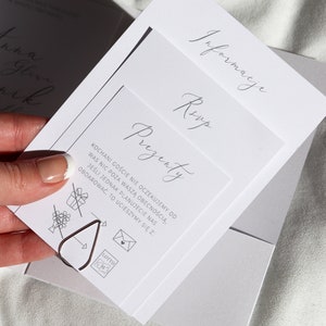 May include: A white card with the text "Prezenty" in cursive script. The card also includes a list of gift ideas, including a bouquet of flowers, a gift box with a ribbon, a letter in an envelope, and a lottery ticket. The text on the card reads: "KOCHANI GOŚCIE NIE OCZEKUJEMY OD WAS NIC POZA WASZĄ OBECNOŚCIĄ. JEŚLI JEDNAK PLANUJECIE NAS ODBDAROWAĆ, TO UCIESZYMY SIĘ Z:"