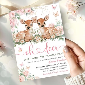 Puede incluir: Invitación a un baby shower con ilustraciones de dos cervatillos rodeados de rosas rosas y mariposas. El texto de la invitación, en escritura rosa, dice "Oh deer, nuestros gemelos están casi aquí". Detalles de la fecha, hora y lugar.