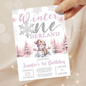 Op de afbeelding: Een roze en witte uitnodigingskaart met de woorden "Winter Wonderland" in een scriptlettertype. De kaart bevat een sneeuwmanillustratie, sneeuwvlokken en de tekst "Jennifer's 1st Birthday".