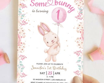 Puede incluir: Una invitación rosa y blanca con un conejito sosteniendo un globo rosa con el número 1. El texto dice "Somebunny is turning 1". La invitación es para el primer cumpleaños de Jennifer, el sábado 25 de abril de 2:00 PM a 4:00 PM. La dirección es 123 Madison Street, Los Angeles, CA. RSVP a Mary al 573-622-5227 antes del 15 de abril.