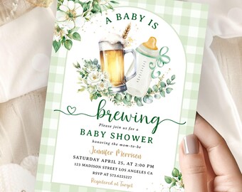 May include: A green and white checkered baby shower invitation with a beer mug and a baby bottle. The text reads "A Baby Is Brewing" and includes details for the event, including the date, time, location, and RSVP information. The invitation is decorated with white flowers and green leaves.