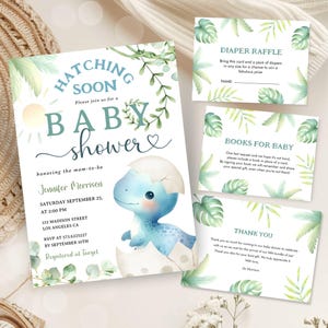 Può includere: Un invito a un baby shower con un dinosauro blu che esce da un uovo. L'invito ha foglie verdi e un sole sullo sfondo. Il testo sull'invito recita "Hatching Soon, Please join us for a Baby Shower, honouring the mom-to-be Jennifer Morrisen, Saturday September 25, at 2:00 PM, 123 Madison Street, Los Angeles CA, RSVP at 573-6225227 by September 10th, Registered at Target".