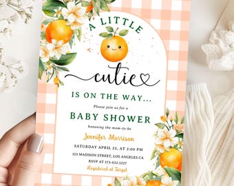 May include: A pink and white gingham baby shower invitation with a cute orange illustration. The text reads "A Little Cutie is on the Way... Please join us for a Baby Shower honoring the mom-to-be Jennifer Morrison Saturday April 25, at 2:00 PM 123 Madison Street, Los Angeles CA RSVP at 573-622.5227 Registered at Target"