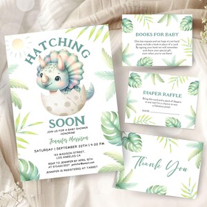 Può includere: Un invito a una festa di benvenuto per un bambino con un simpatico dinosauro dei cartoni animati che sguscia da un uovo. L'invito è decorato con foglie verdi e contiene il testo "Hatching Soon" e "Jennifer Morrison".
