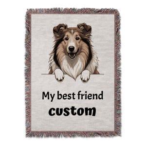 Op de afbeelding: Geweven plaid met een illustratie van een lachende hond in bruin en wit. De hond kijkt over een witte banner met de tekst "My best friend custom". De plaid heeft een gefranjerde rand. Ongeveer 152 cm x 127 cm.