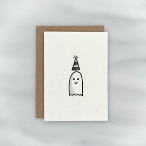 May include: A white ghost with a black and white party hat on a white card with a brown border.