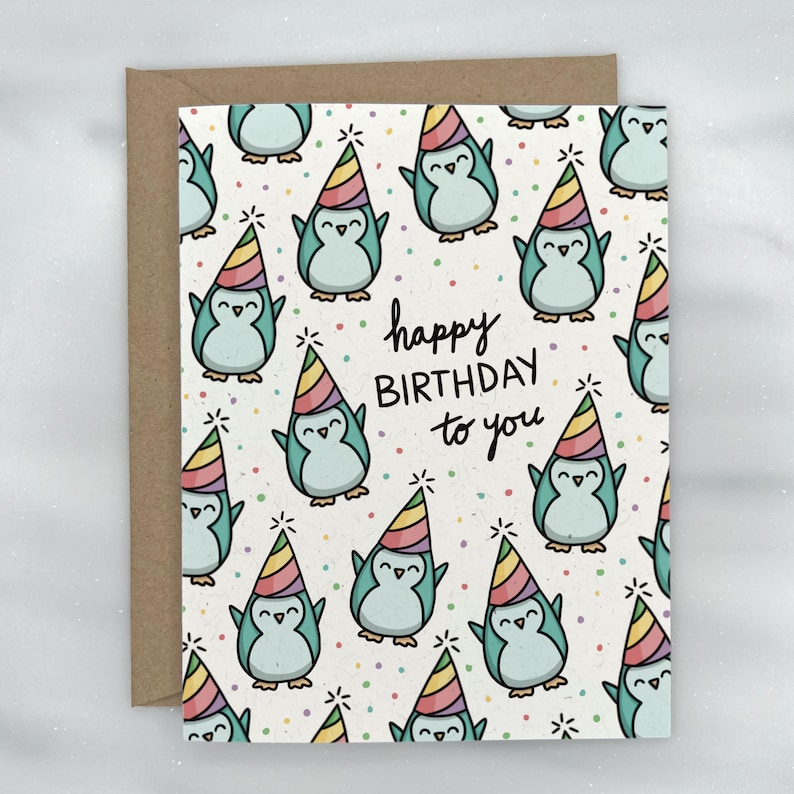 May include: A birthday card with a repeating pattern of cartoon penguins wearing party hats. The penguins are light blue with black outlines, and the hats are rainbow-colored. The words "happy BIRTHDAY to you" are written in black.