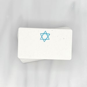 May include: A stack of white note cards with a blue Star of David printed on the top card.